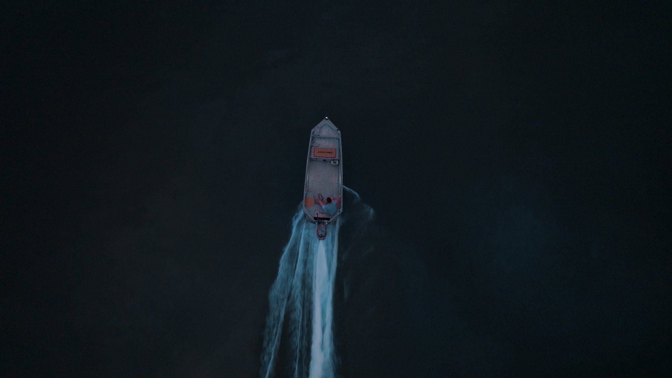 Aerial view of the Divine Outdoors Co. boat running the river at night